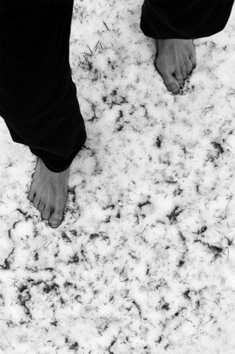 Foto der eigenen Füße beim Gang durch leicht beschneites Gras